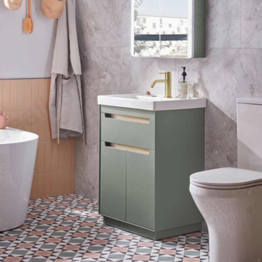 Lifestyle image of the Tavistock Acumen 600mm Laurel Green Freestanding Vanity Unit & Basin installed in a bathroom next to a close-coupled toilet and bathtub